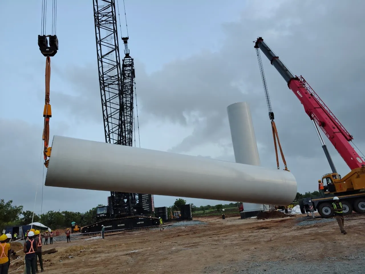 Wind turbine tower section being lifted by crane on site